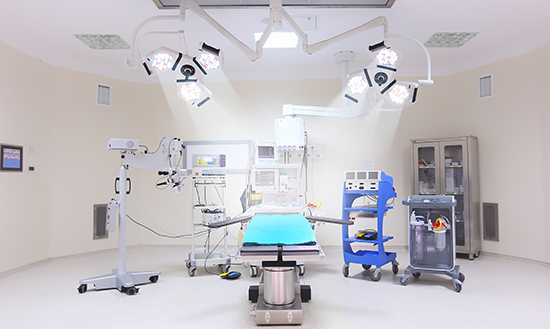 Fully equipped modern operating room with surgical lights, patient table, anesthesia machine, and advanced medical equipment